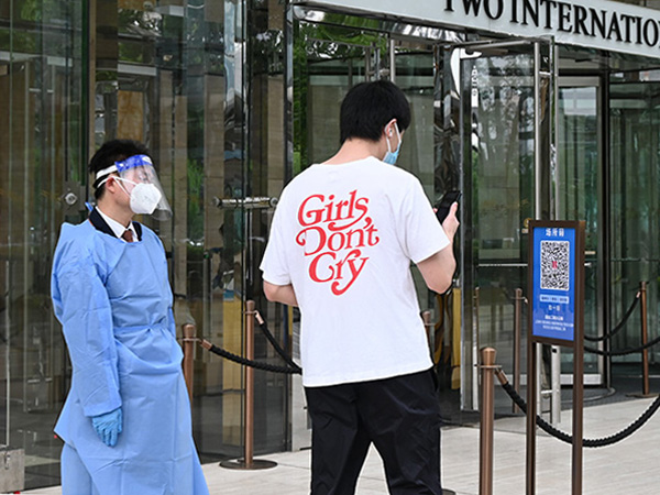 オフィス街、陸家嘴のビル前の出勤風景。ビルに入る際は出入り口に設置された「場所コード」という２次元コードをスマートフォンで読み取る必要がある＝６月１日、中国・上海市